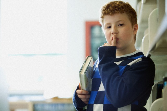 Elementary student making be quiet gesture.